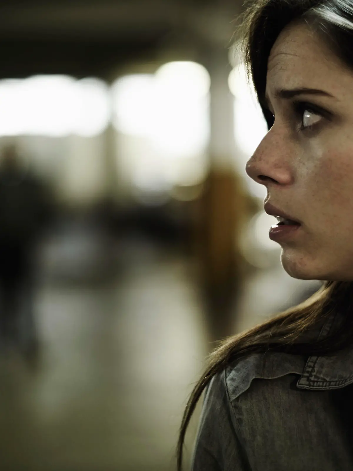 A terrified young woman in an underground parking garage being followed by a sinister man