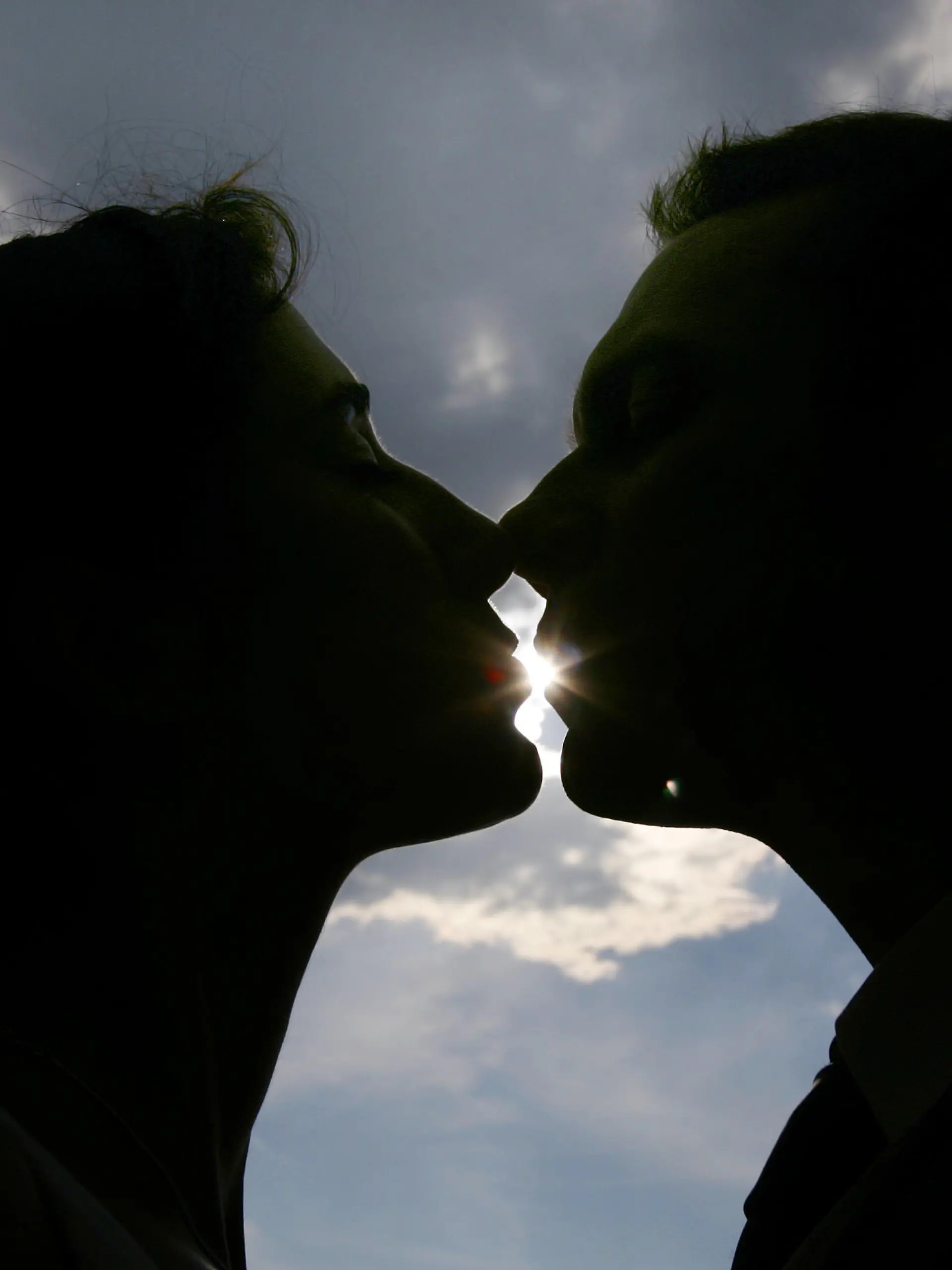 ARCHIV - Die Sonne scheint zwischen den Lippen eines jungen Paares hindurch, während sich die beiden in Koblenz küssen  (Archivfoto vom 30.07.2007). Beim Küssen sorgen Hormone im Blut und Botenstoffe, wie Dopamin und Serotonin, im Gehirn, dafür, dass sich der Mensch glücklich fühlt. Eine wahre "Glückshysterie" scheint momentan um sich zu greifen. Die Menschen sind stets auf der Suche nach Glück, denn Glück ist ein Wohlgefühl, und es liegt natürlich nahe, sich immer wohlfühlen zu wollen. Foto: Frank May dpa (zu dpa-Reportage: "'Glückshysterie' ausgebrochen: Wie wir dabei nicht unglücklich werden" vom 15.01.2008) +++(c) dpa - Bildfunk+++