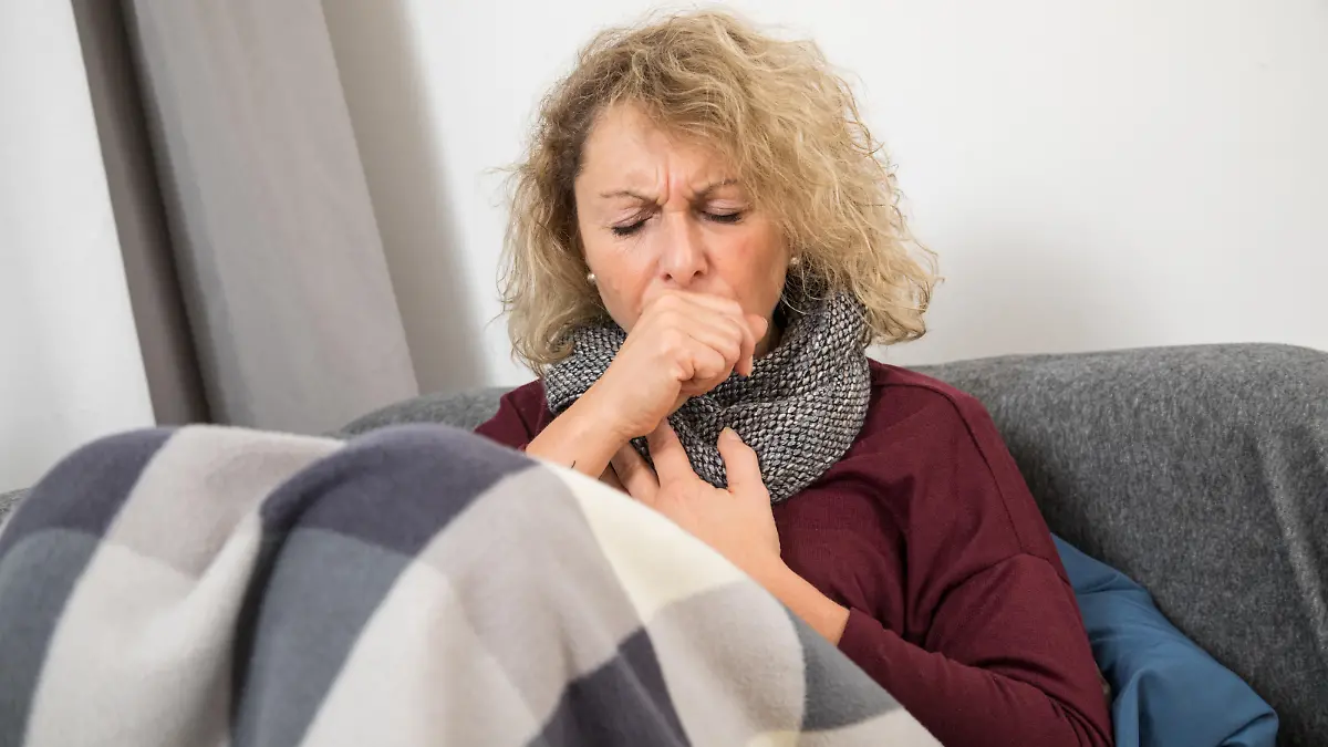 Eine Frau liegt auf einer Couch und hat Reizhusten