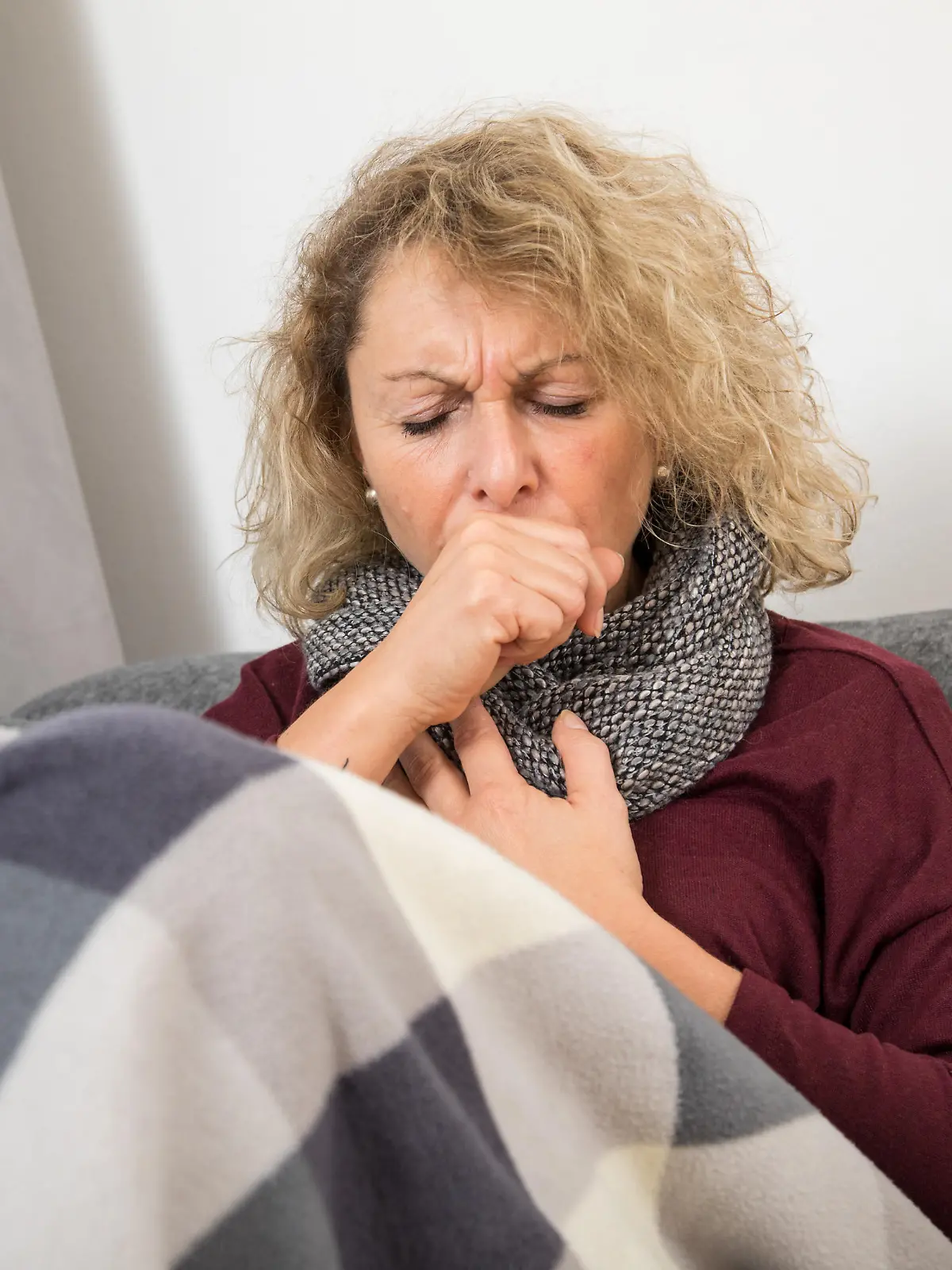 Eine Frau liegt auf einer Couch und hat Reizhusten