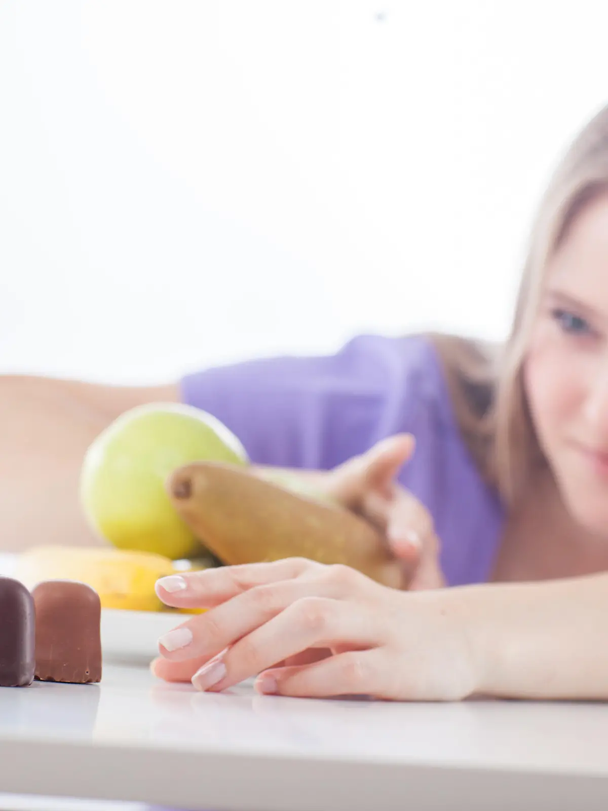 ILLUSTRATION - Eine junge Frau hat am 15.06.2016 in Hamburg die Wahl zwischen Obst und Schokokuessen. Foto: Christin Klose | Verwendung weltweit