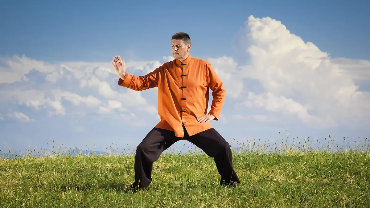 Mann praktiziert Qi-Gong-Übungen auf einer Wiese