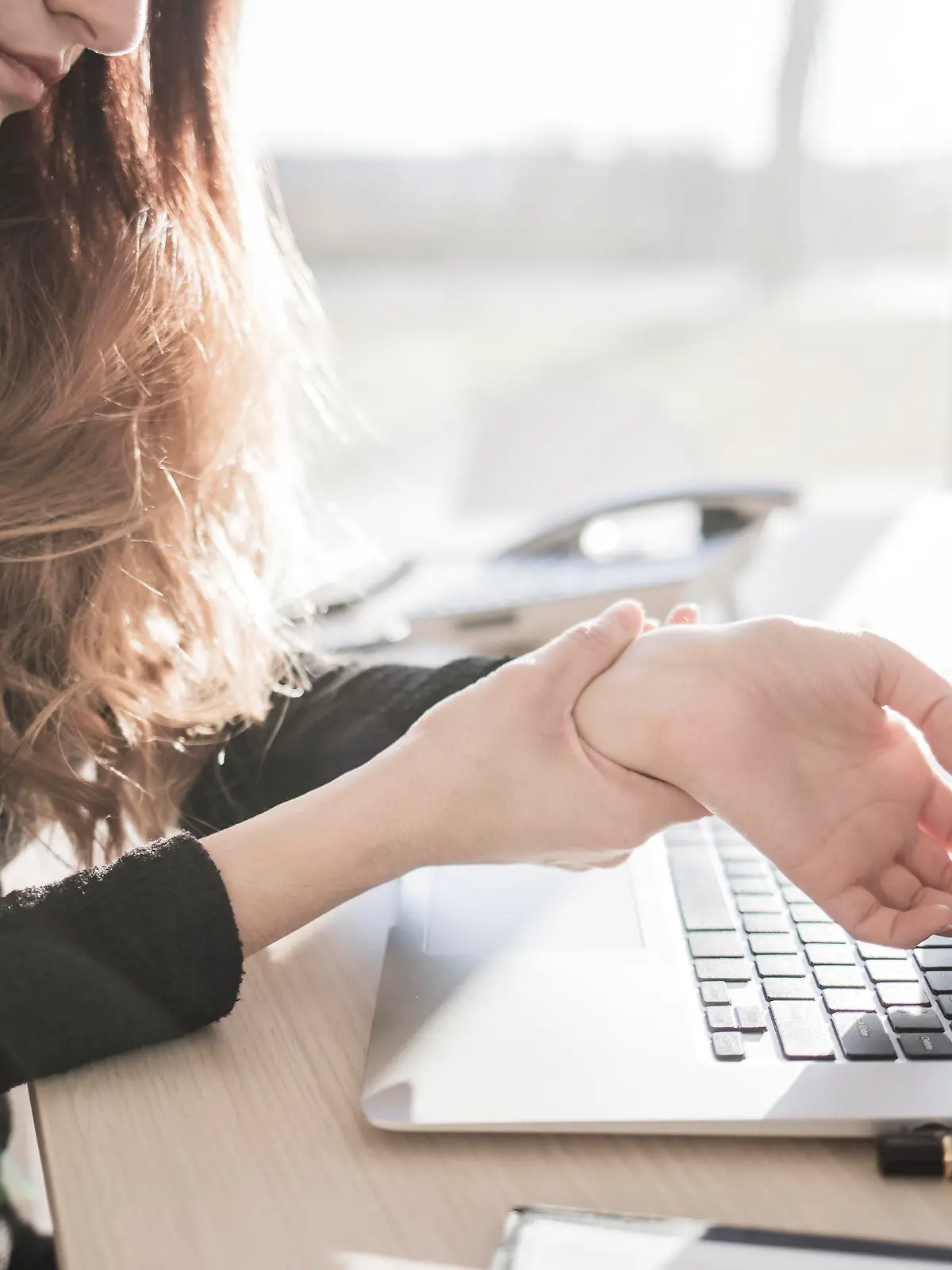 Frau mit Sehnenscheidenentzündung am Computer