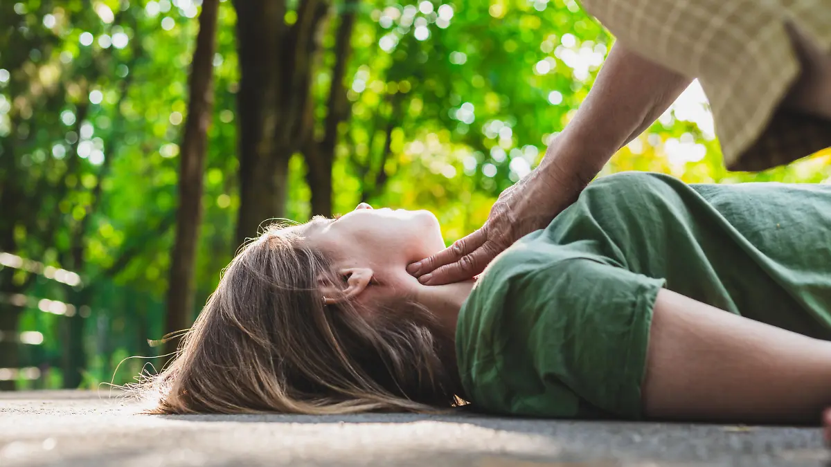 Frau überprüft den Puls eines jungen ohnmächtigen Mädchens