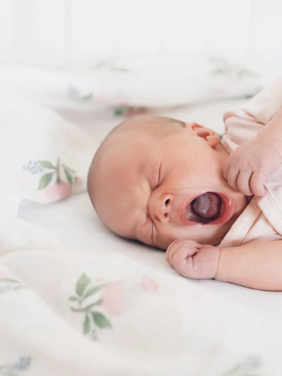 Neugeborenes Baby gähnt und hat eine weißliche Zunge, ein Zeichen für Mundsoor.