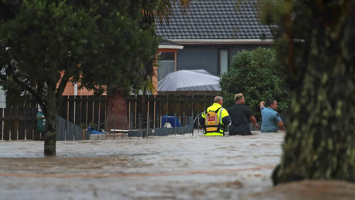 Emergency workers and a man wade through flood waters in Auckland, New Zealand, Friday, Jan. 27, 2023. Torrential rain and wild weather in Auckland causes disruptions throughout the city and an Elton John concert to be canceled just before it was due to start. (Hayden Woodward/New Zealand Herald via AP)