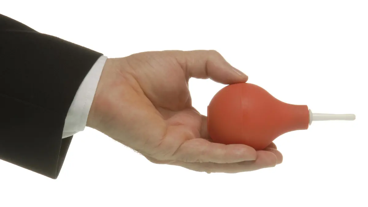 Businessmann mit Klistier (Einlauf verpassen)