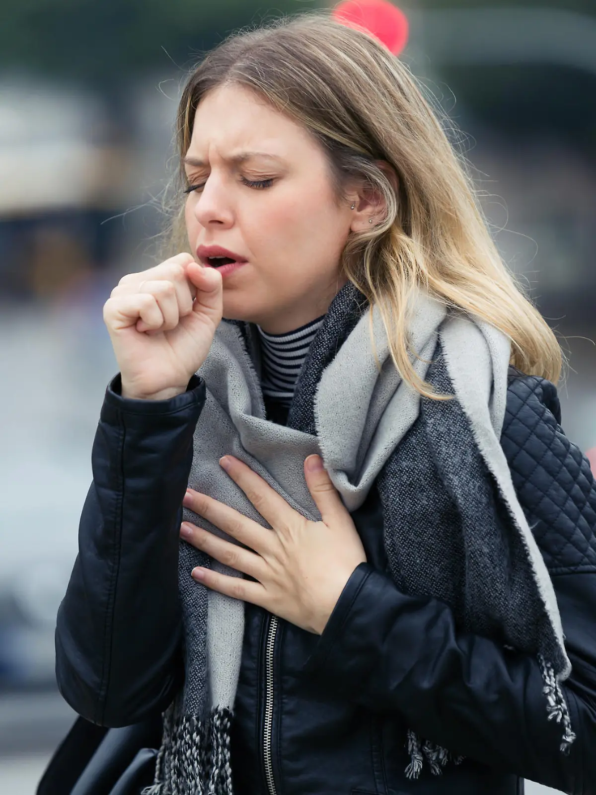 Shot of illness young woman coughing in the street.