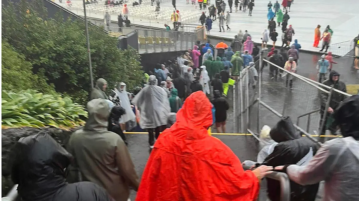 Fans leave Mt Smart Stadium in Auckland, New Zealand, Friday, Jan. 27, 2023, where about 40,000 people were expected to attend an Elton John concert. Torrential rain and wild weather in Auckland causes disruptions throughout the city and an Elton John concert to be canceled just before it was due to start. (Julea Dalley/New Zealand Herald via AP)