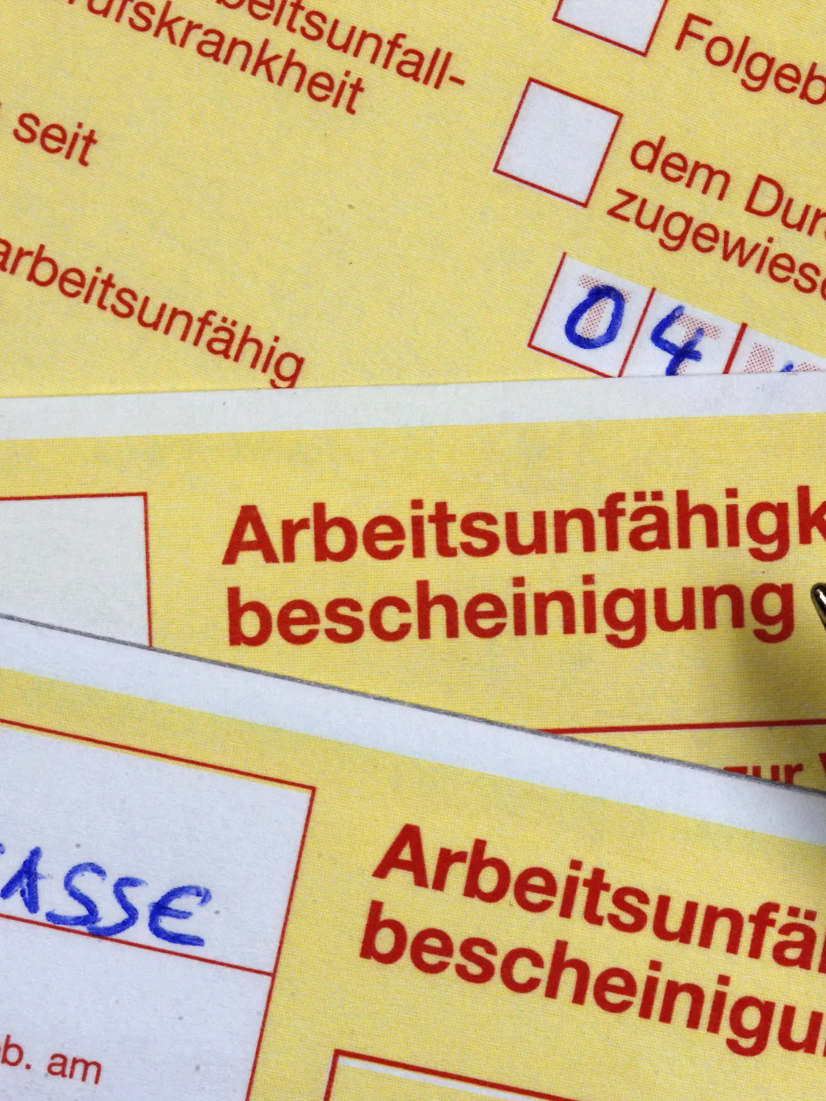 ILLUSTRATION - ARCHIV - Arbeitsunfähigkeitsbescheinigungen liegen am 12.10.2009 auf einem Schreibtisch in Schwerin. Foto: Jens Büttner/dpa (zu dpa "Psychologe: Trotz Krankheit Arbeiten verbreiteter als Blaumachen" vom 31.10.2015) +++(c) dpa - Bildfunk+++