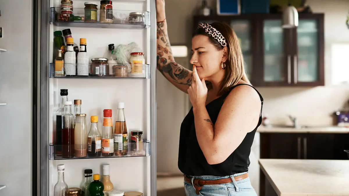 Shot of a young woman searching inside a refrigerator at home