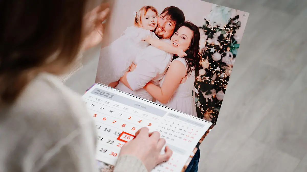 A woman looks at a calendar with a family photo. A useful gift with your photos. Souvenir. additional photographer's service.