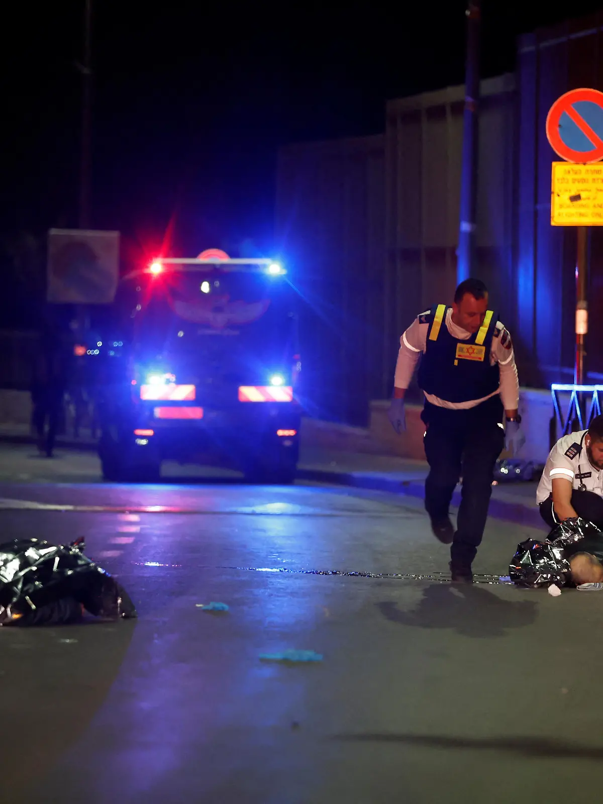 Israeli forces walk next to dead covered bodies at the scene of a shooting attack in Neve Yaacov which lies on occupied land that Israel annexed to?Jerusalem?after the 1967 Middle East war January 27, 2023. REUTERS/Ammar Awad