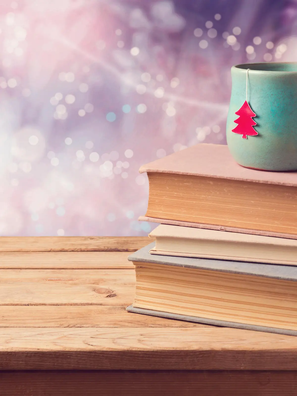 Christmas cup of tea and vintage books on wooden table over beautiful winter bokeh background with copy space