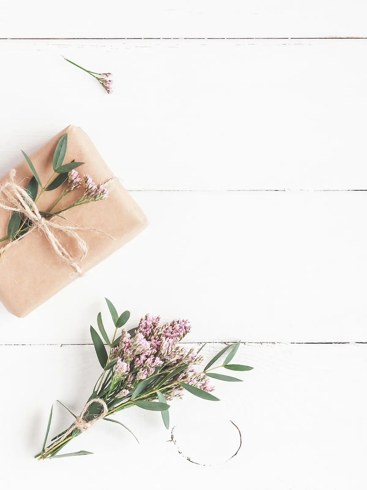 Flowers composition. Gift, pink flowers and eucalyptus branches on white wooden background. Flat lay, top view