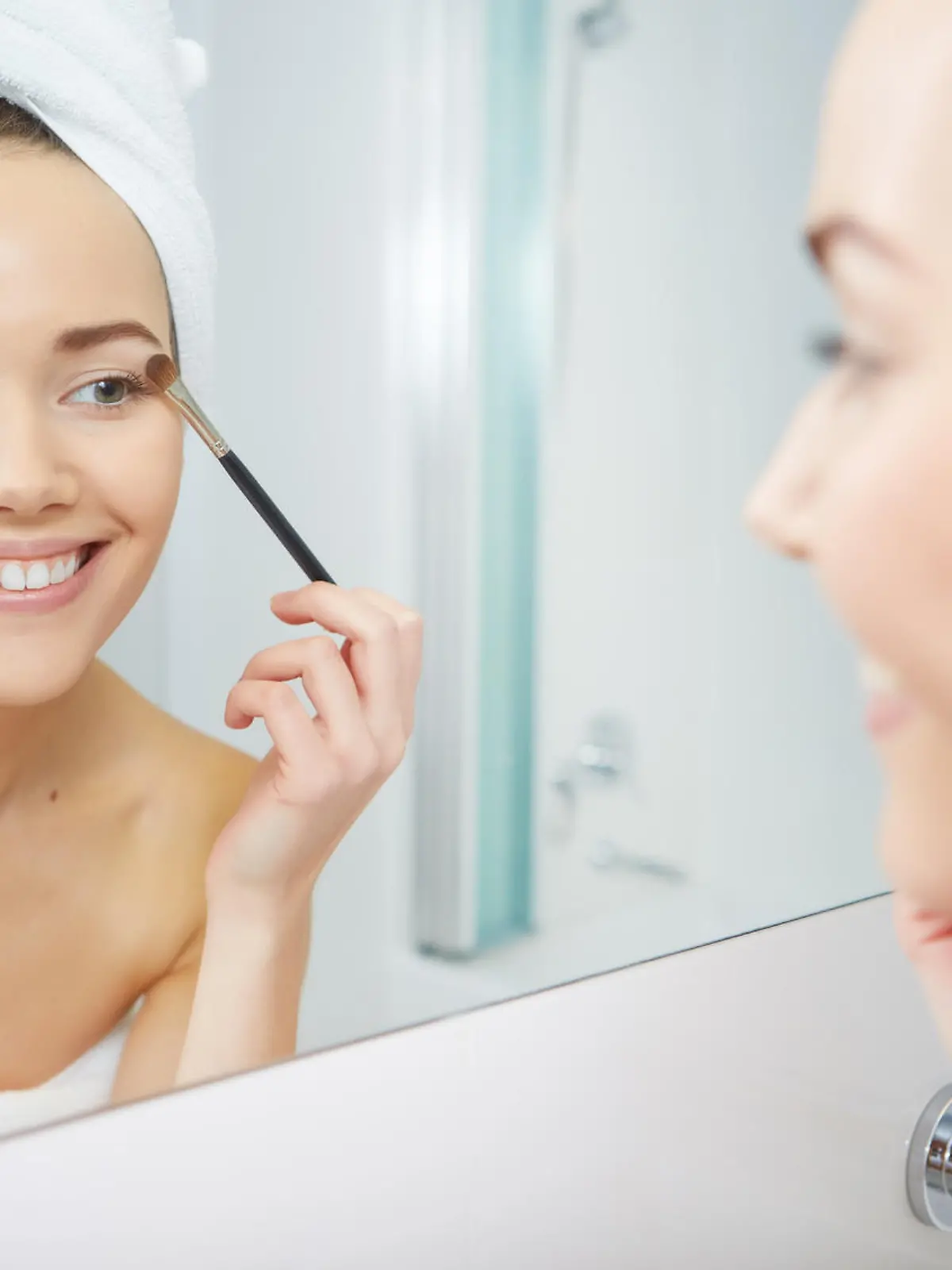 A picture of a young woman applying face powder in the bathroom