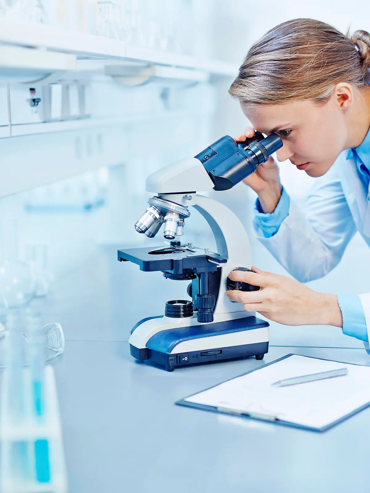 Young scientist studying new substance or virus in microscope