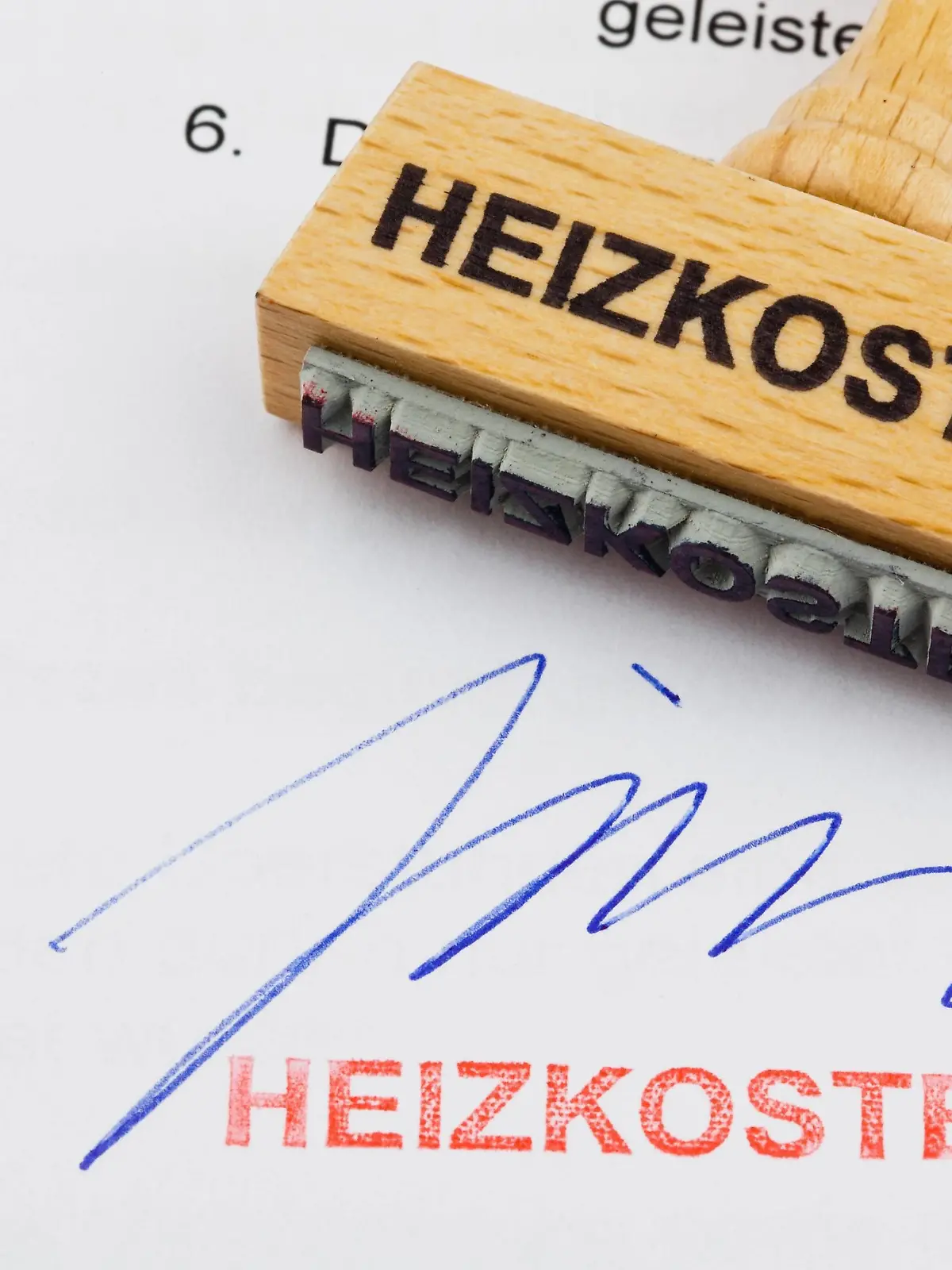  Ein Stempel aus Holz liegt auf einem Dokument. Deutsche Aufschrift: Heizkosten McPBBO McPBBO