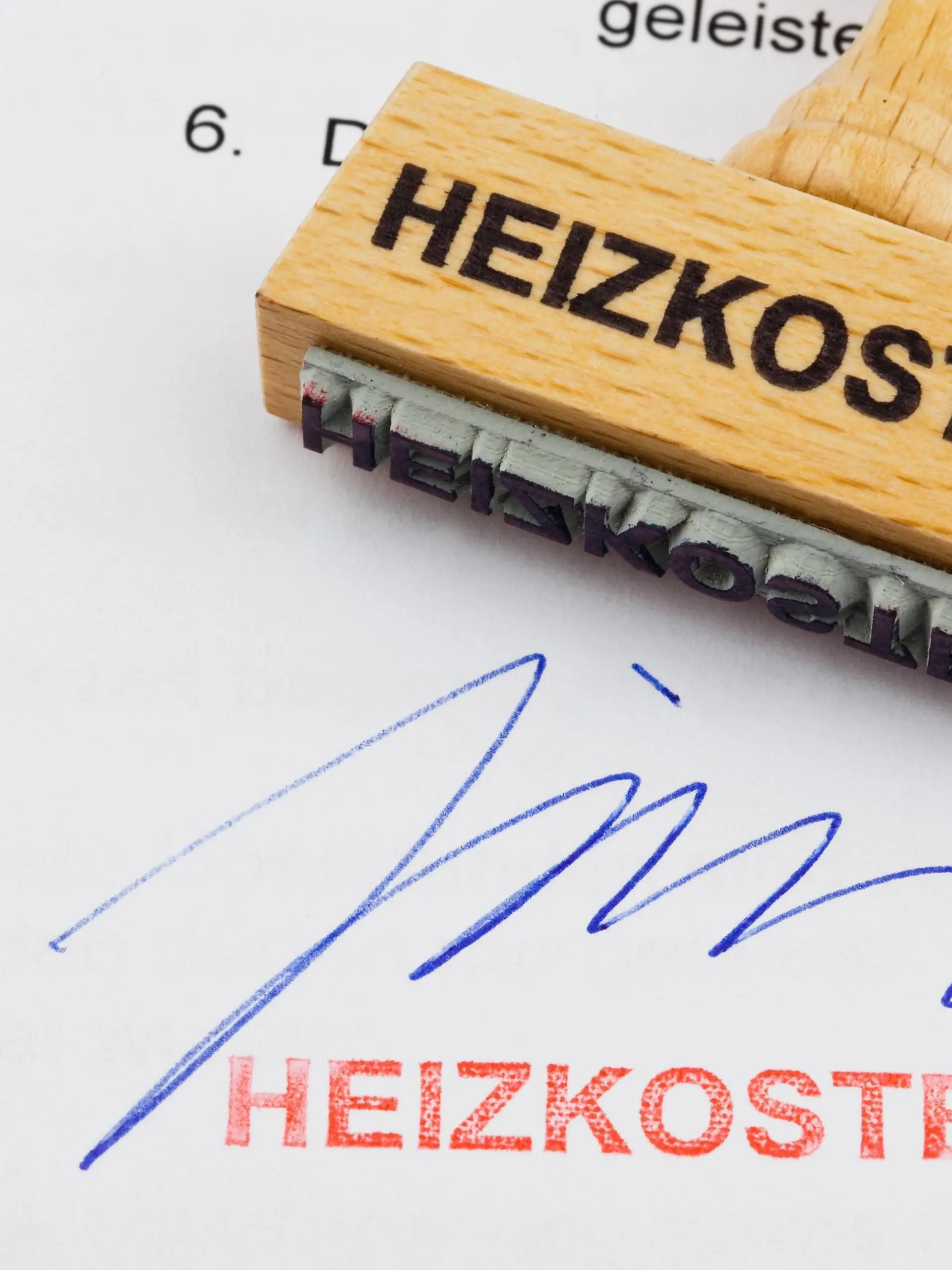  Ein Stempel aus Holz liegt auf einem Dokument. Deutsche Aufschrift: Heizkosten McPBBO McPBBO