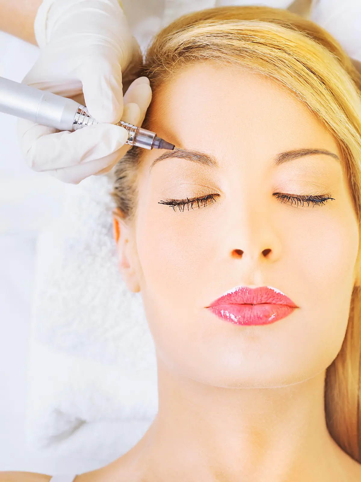 Cosmetologist applying permanent make up on eyebrows