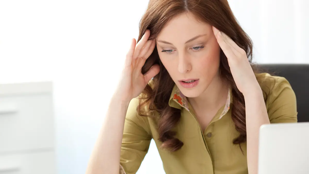 "Young Businesswoman Having Headache in the office, doing massage of the head and sitting at the desk."