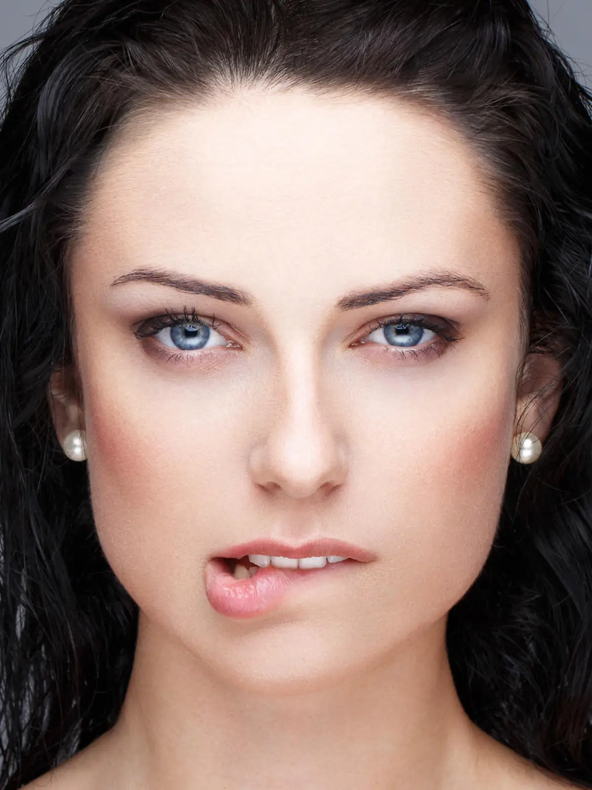 Sexy brunette woman bite lips portrait on grey