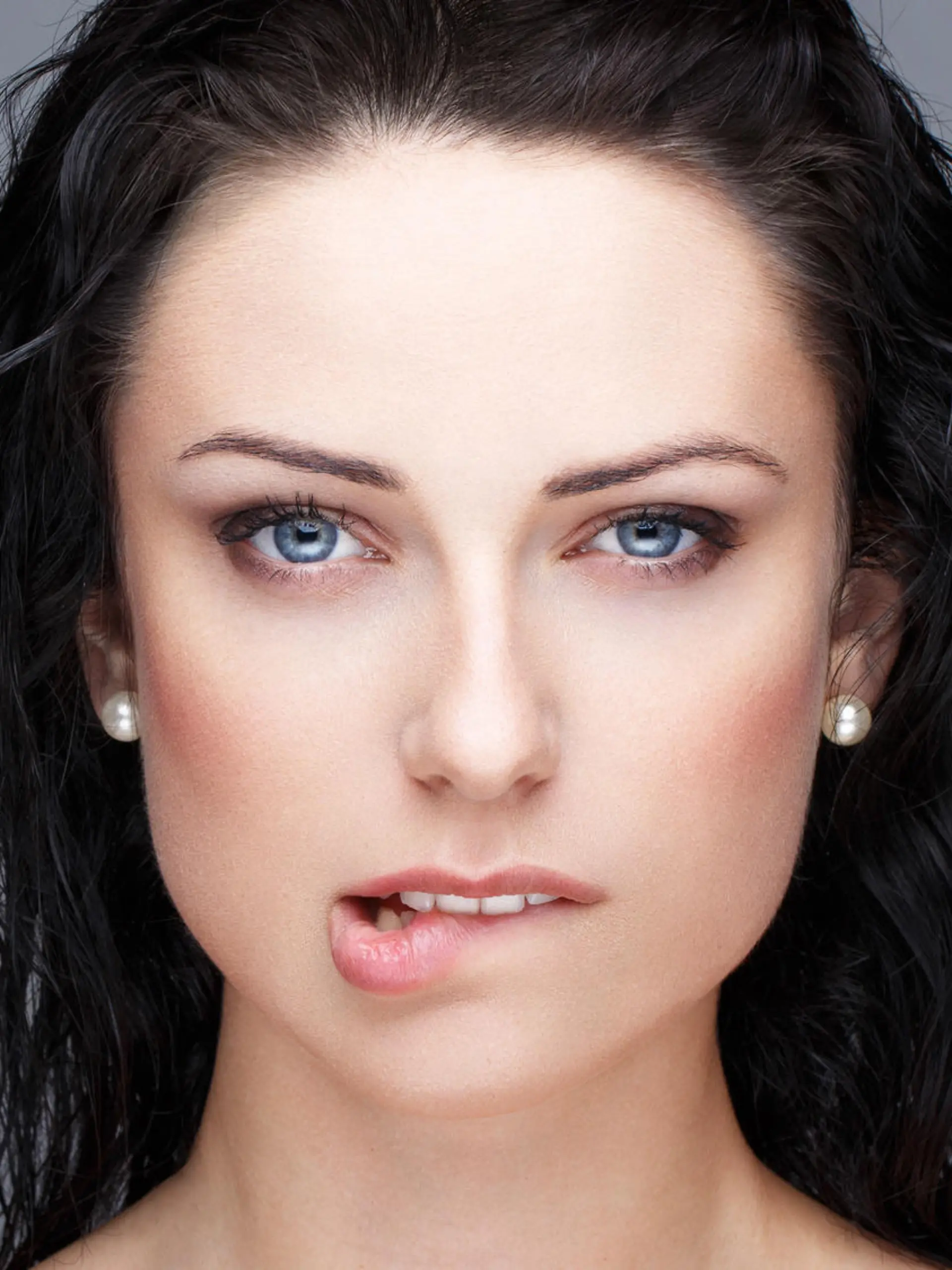 Sexy brunette woman bite lips portrait on grey
