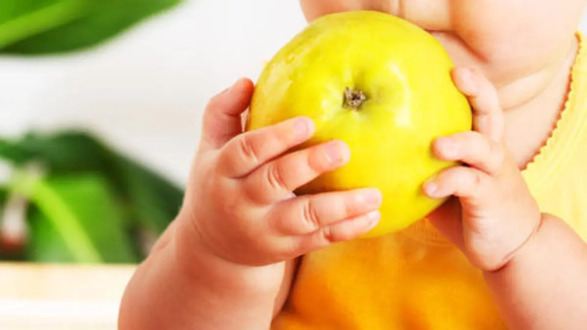 Little baby eating apple, closeup portrait, concept of health care & healthy child nutrition