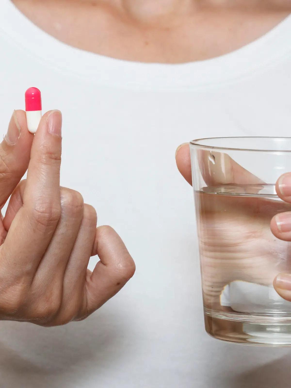 hands holding capsule pill and a glass of water