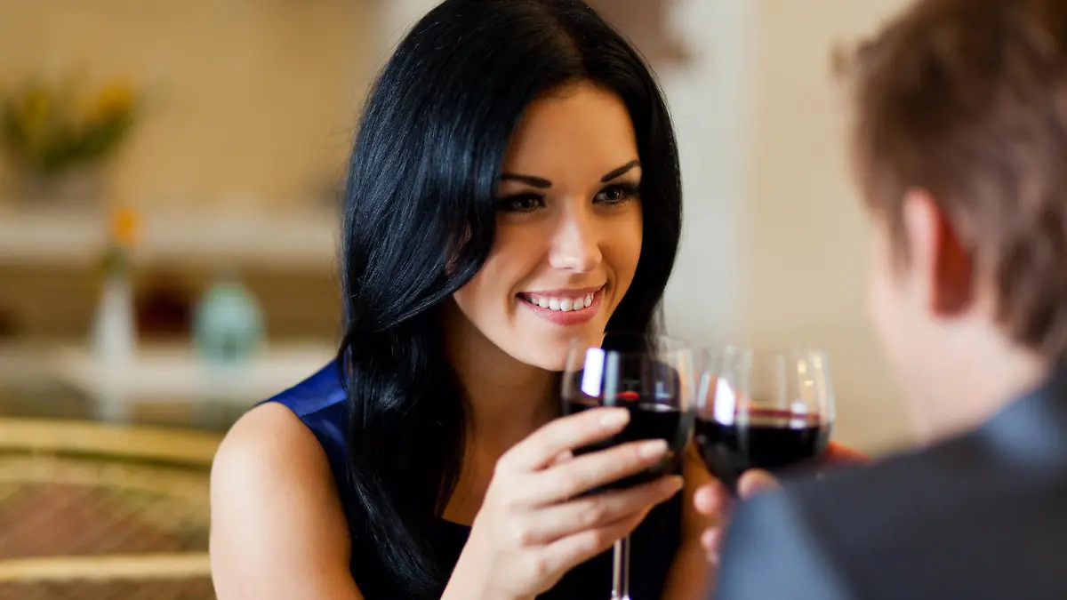 Young happy couple romantic date drink glass of red wine at restaurant, celebrating valentine day