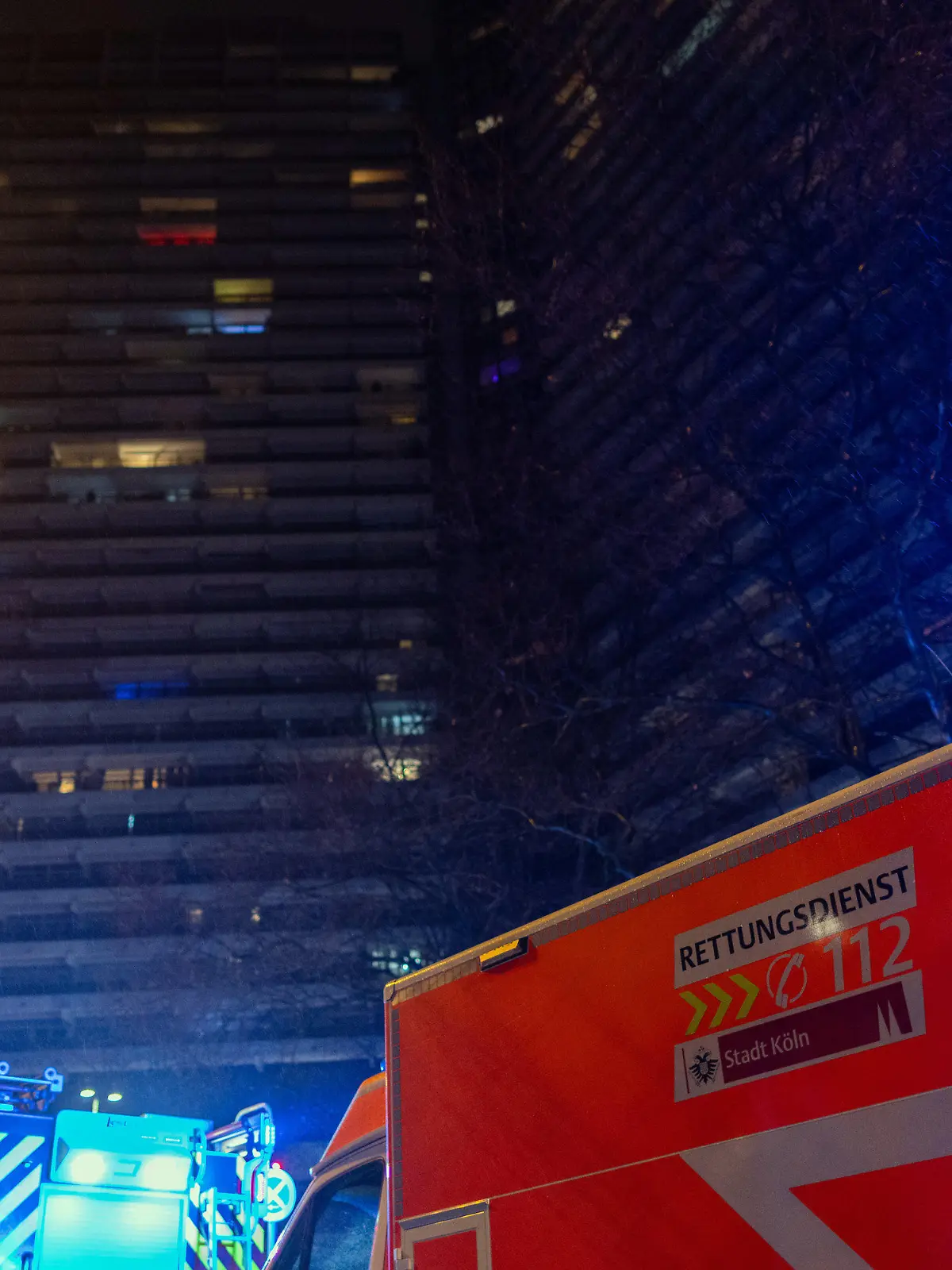 PRODUKTION - 26.01.2023, Nordrhein-Westfalen, Köln: Einsatzkräfte der Feuerwehr stehen vor dem Uni-Center. Im Uni-Center Köln, das als eines der größten Wohnhäuser in Europa gilt, ist am Donnerstagabend ein Feuer ausgebrochen. Mehrere Anrufer hätten Rauch gemeldet, dieser breite sich über alle 42 Stockwerke aus, sagte ein Feuerwehrsprecher. 50 bis 60 Bewohner seien evakuiert worden. Foto: Rolf Vennenbernd/dpa +++ dpa-Bildfunk +++
