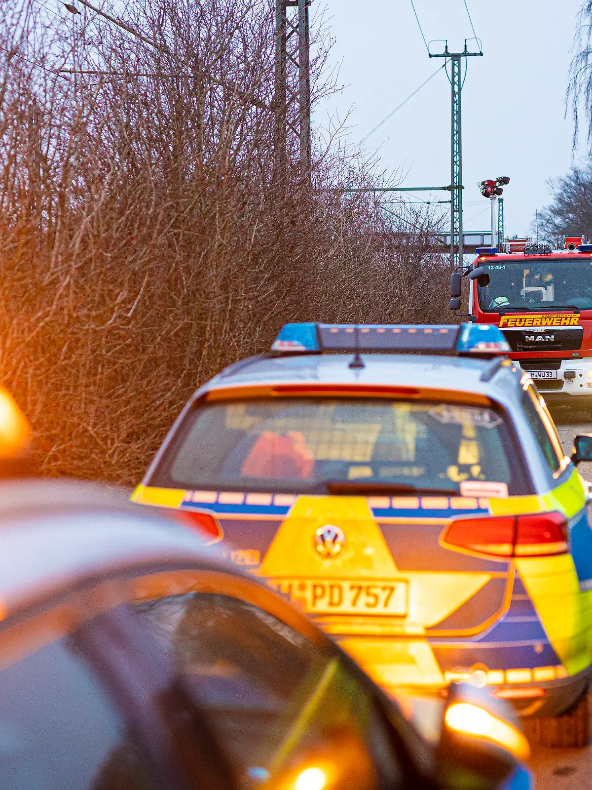 25.01.2023, Niedersachsen, Wunstorf: Einsatzfahrzeuge von Polizei und Feuerwehr stehen an einem Waldstück in der Region Hannover. Auf der Suche nach einem mutmaßlich getöteten Jugendlichen durchkämmen Einsatzkräfte ein Waldgebiet im niedersächsischen Wunstorf. Foto: Moritz Frankenberg/dpa +++ dpa-Bildfunk +++