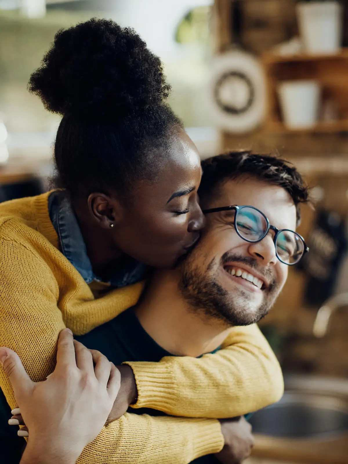 Young African American woman kissing her boyfriend having fun with him at home.