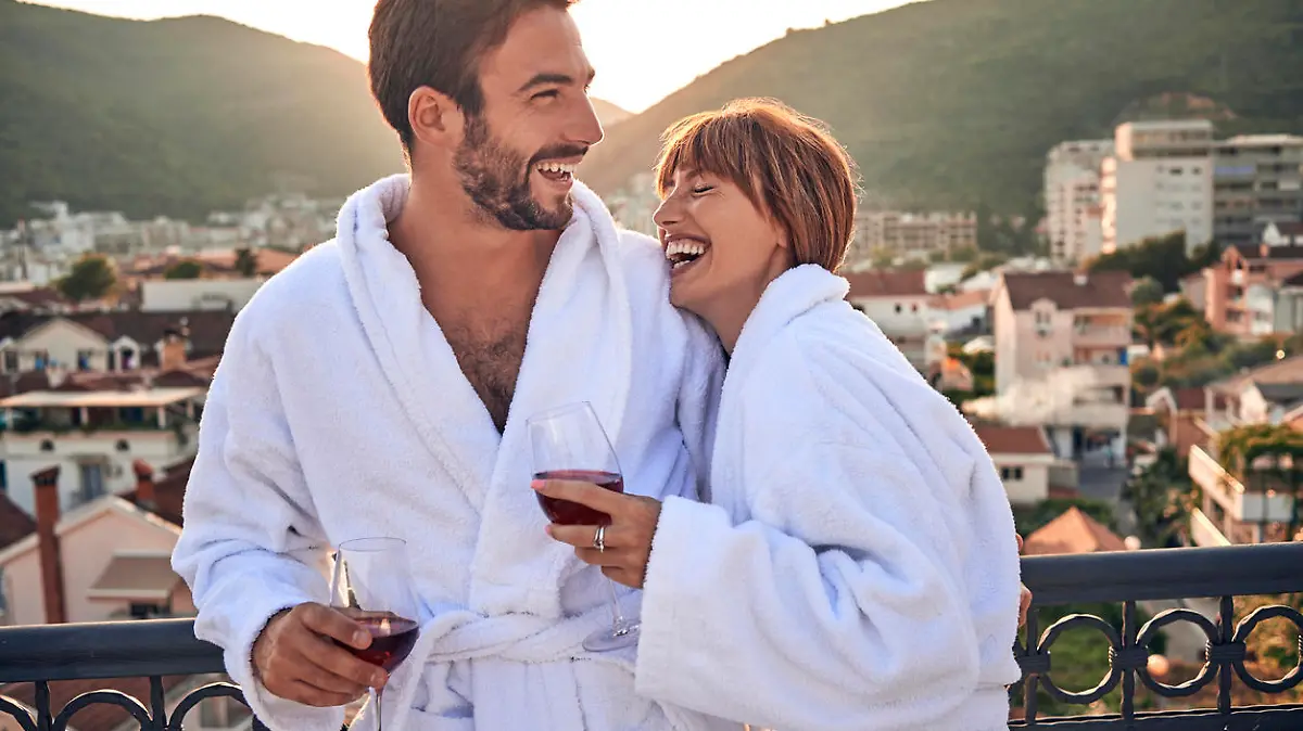 relaxed couple having a wine on the balcony with a view in their bathrobes