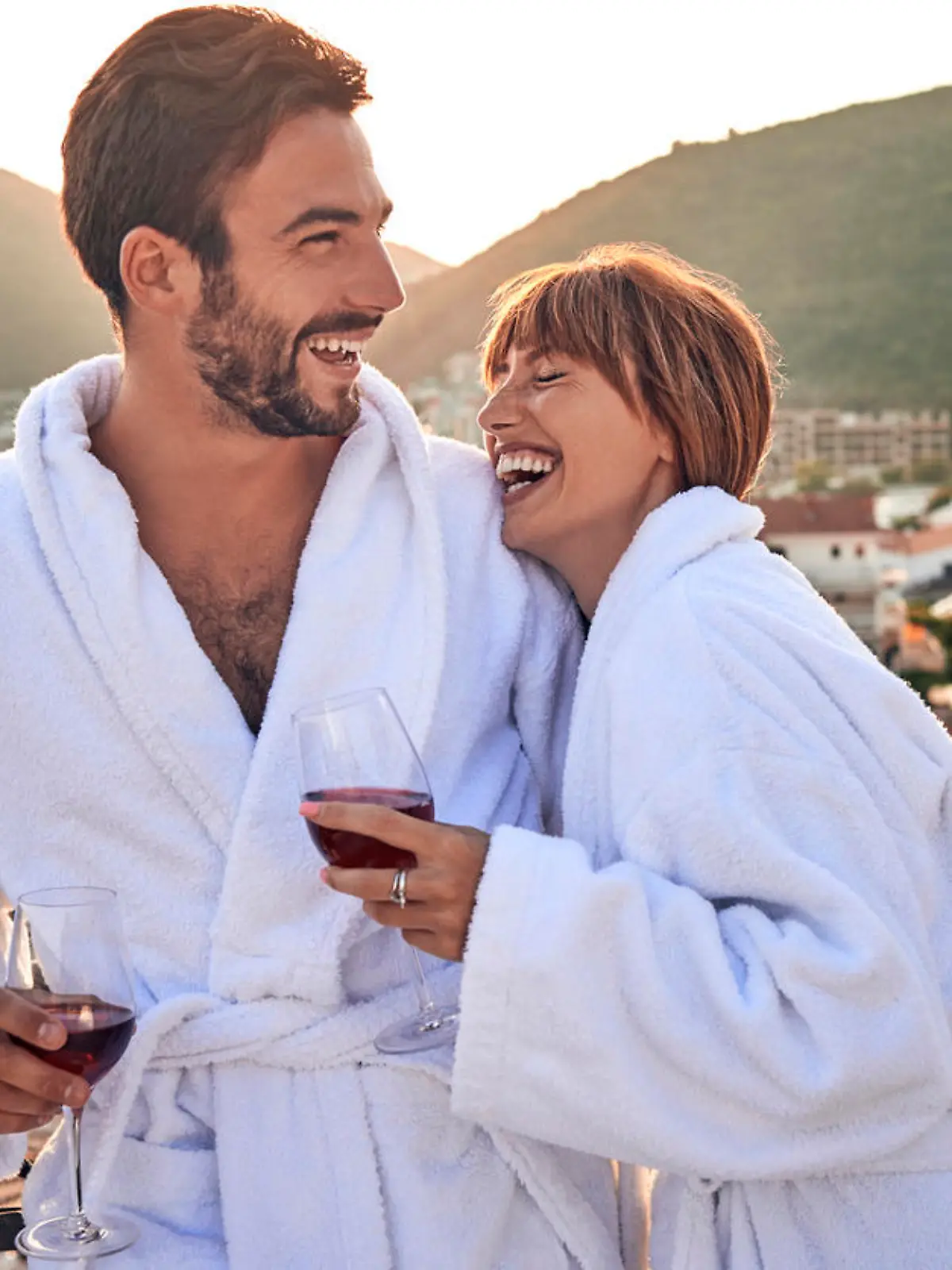 relaxed couple having a wine on the balcony with a view in their bathrobes