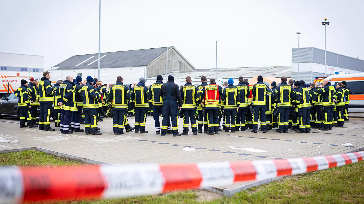 25.01.2023, Niedersachsen, Wunstorf: Einsatzkräfte der Feuerwehr besprechen sich auf dem Parkplatz einer Spedition in der Region Hannover. Auf der Suche nach einem mutmaßlich getöteten Jugendlichen durchkämmen Einsatzkräfte ein Waldgebiet im niedersächsischen Wunstorf. Foto: Moritz Frankenberg/dpa +++ dpa-Bildfunk +++