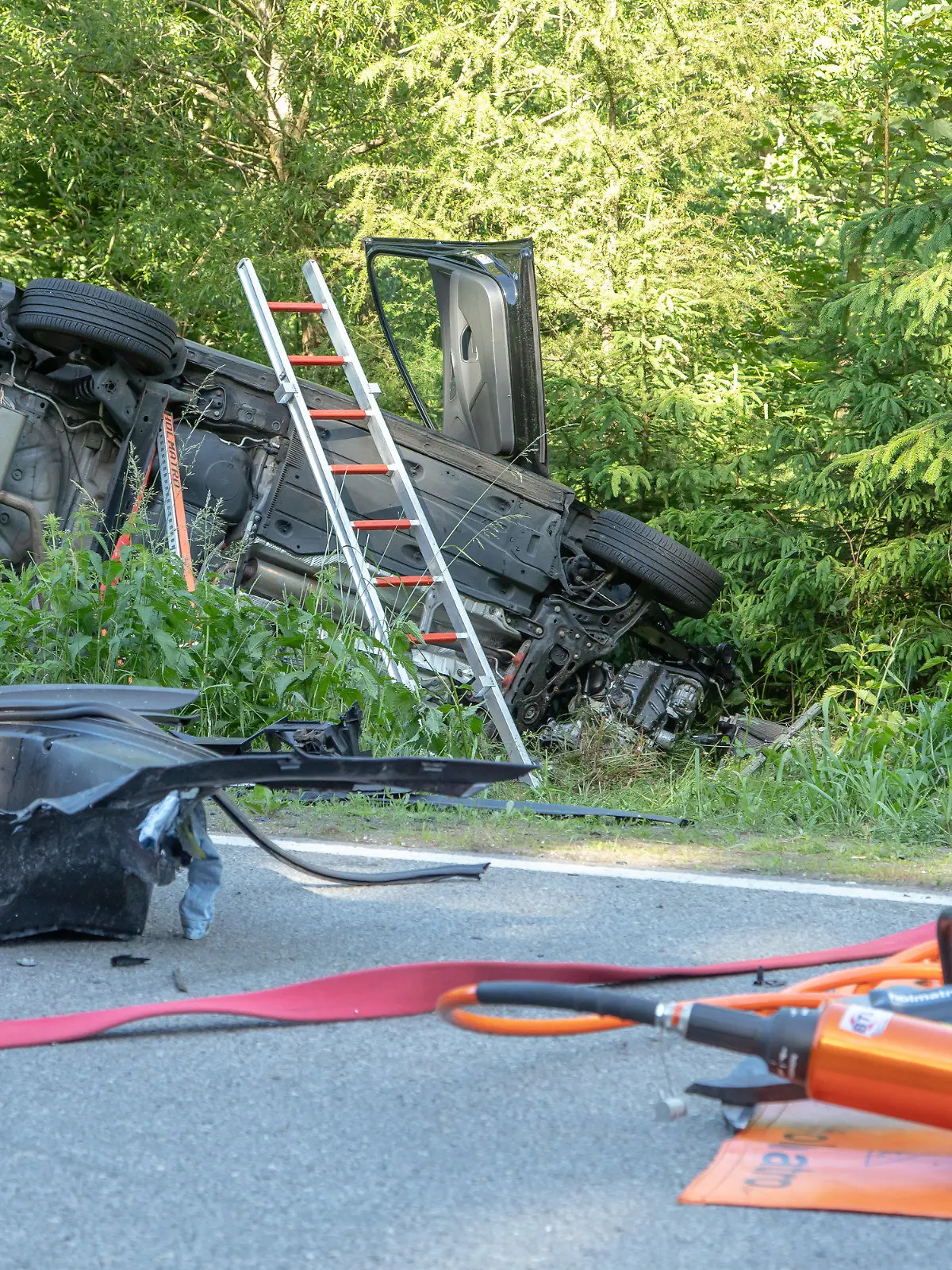 21.06.2020, Sachsen, Aue: Rettungswerkzeuge liegen neben einem Auto, das im Graben liegt. Beim Zusammenstoß von zwei Autos im Erzgebirgskreis sind am Sonntag drei Menschen gestorben. Eine Frau und zwei Kinder wurden verletzt, wie die Polizei Chemnitz mitteilte. Foto: Andre März/dpa-Zentralbild/dpa +++ dpa-Bildfunk +++