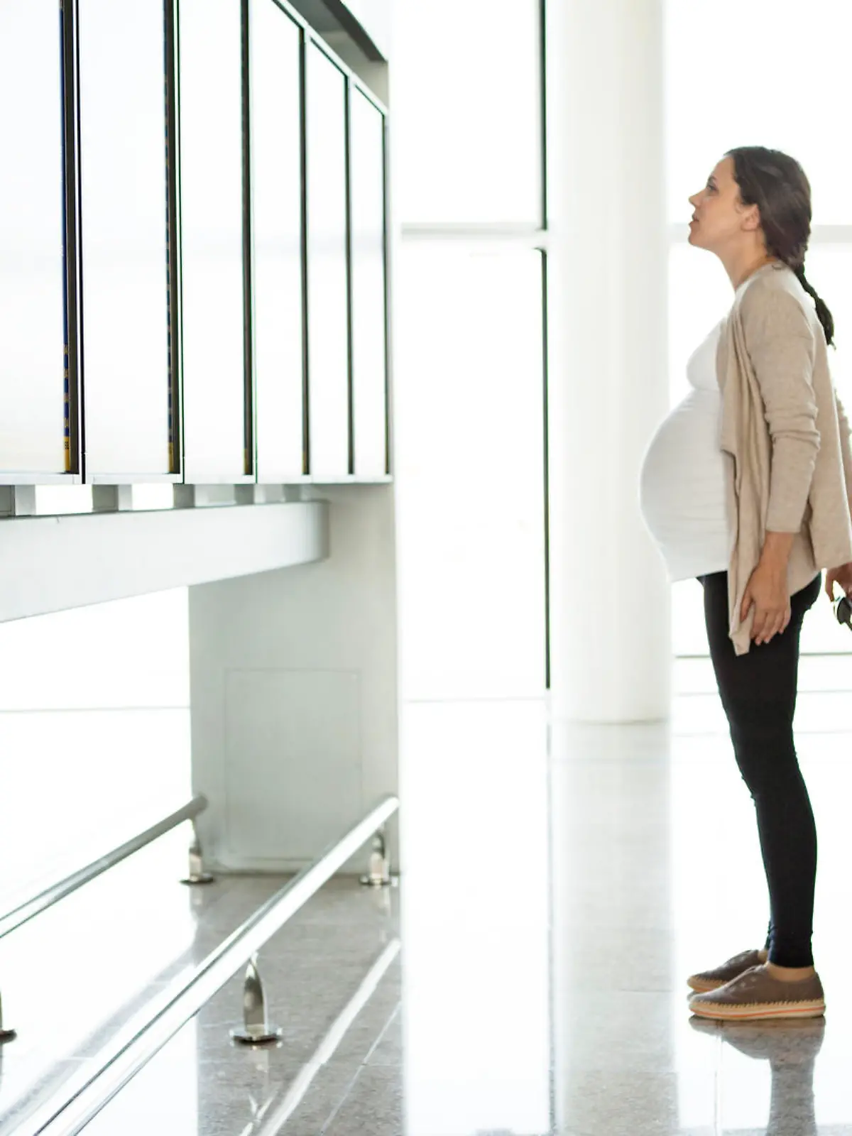 Pregnant woman looking at departure monitor