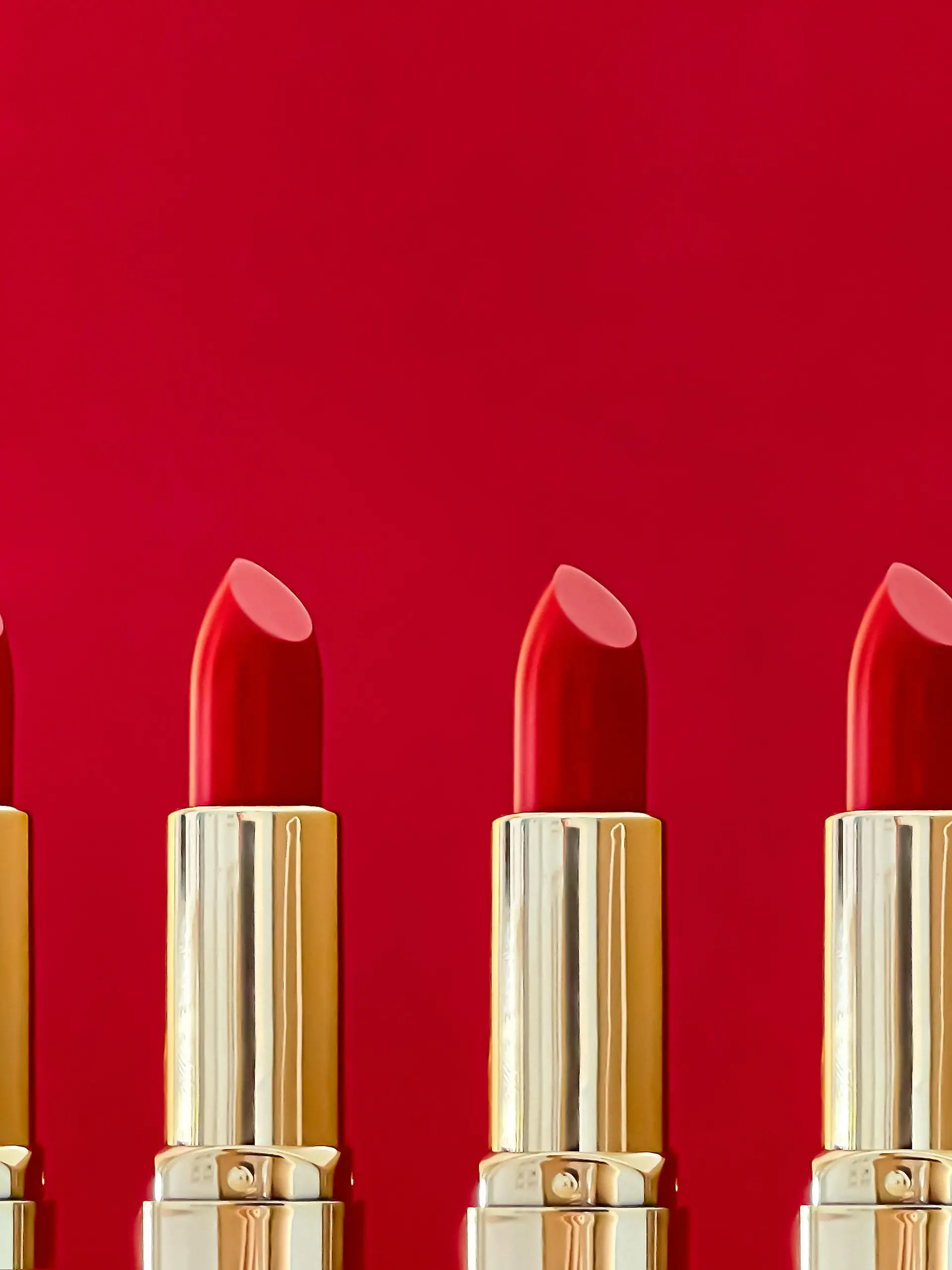 Red lipstick in golden tubes on colour background, luxury make-up and cosmetics for beauty brand product design concept