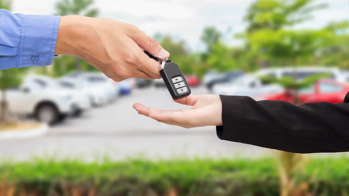 Businesswomen giving a key car to businessman at car parking.
