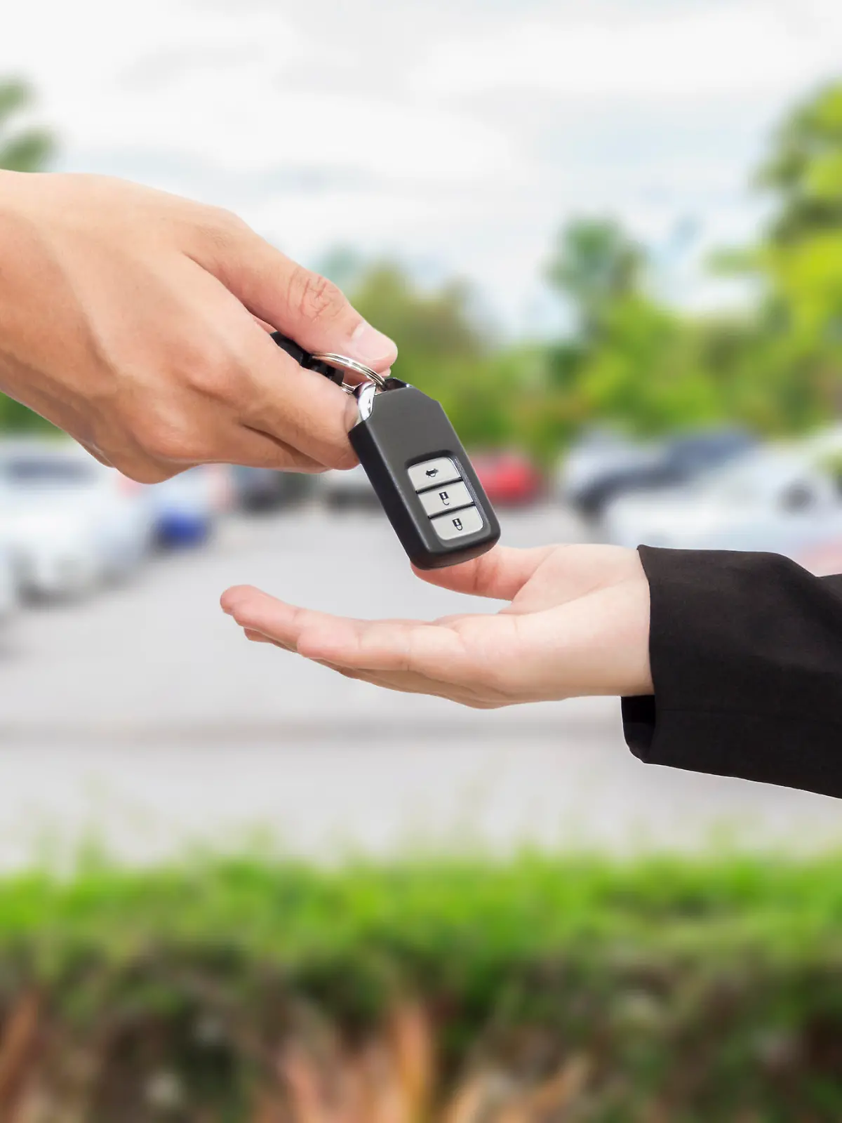 Businesswomen giving a key car to businessman at car parking.