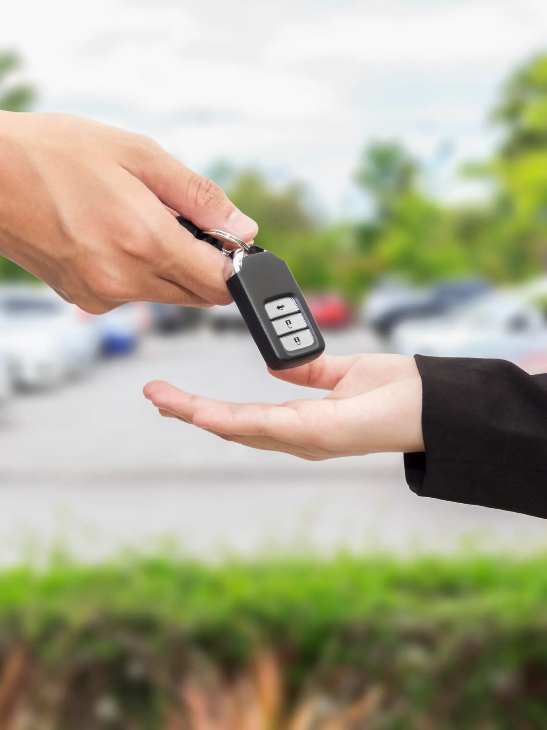 Businesswomen giving a key car to businessman at car parking.