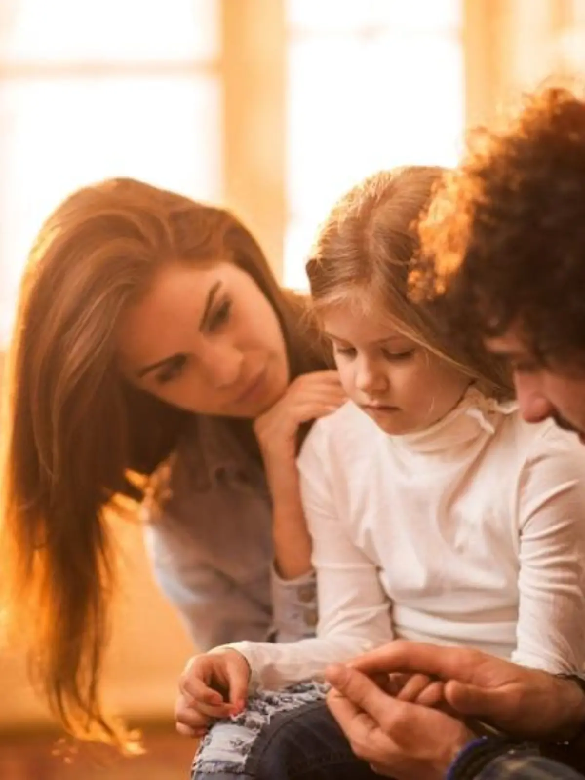 Young parents spending time with their small daughter and consoling her.
