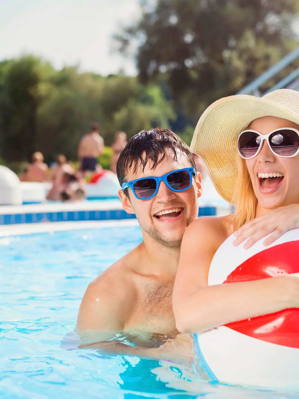 Beautiful young couple having fun outside in the swimming pool