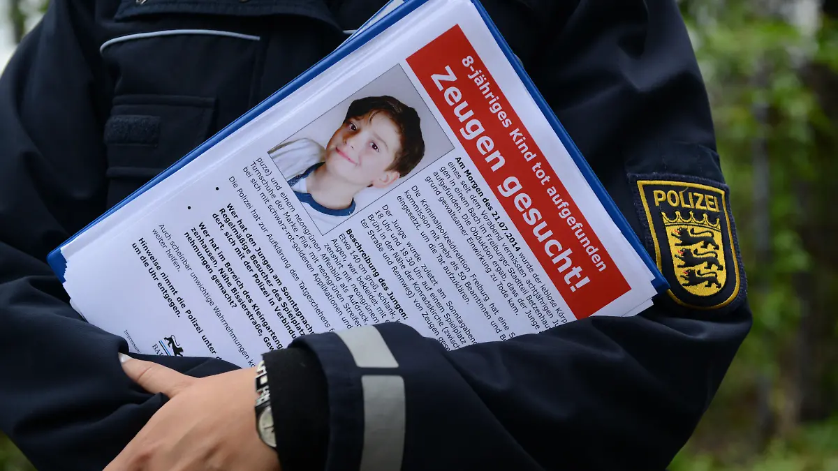 ARCHIV - Eine Polizeibeamtin hält am 22.07.2014 in Freiburg (Baden-Württemberg) am Fundort ein Flugblatt mit einem Foto des getöten achtjährigen Jungen in den Händen. Foto: Patrick Seeger/dpa (zu lsw: ««Aktenzeichen XY» bringt keinen Durchbruch im Mordfall Armani» vom 07.08.2014) +++(c) dpa - Bildfunk+++