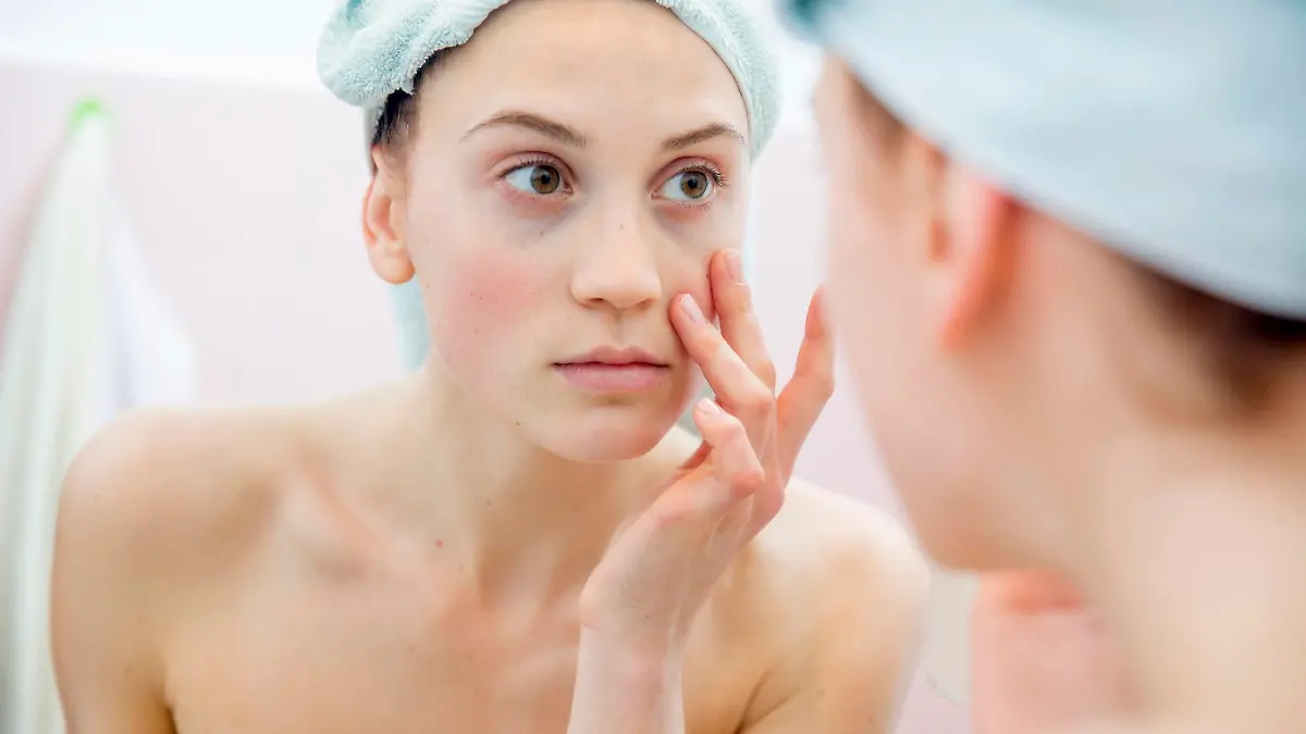 Young woman portrait in the mirror of her bathroom after taking shower.