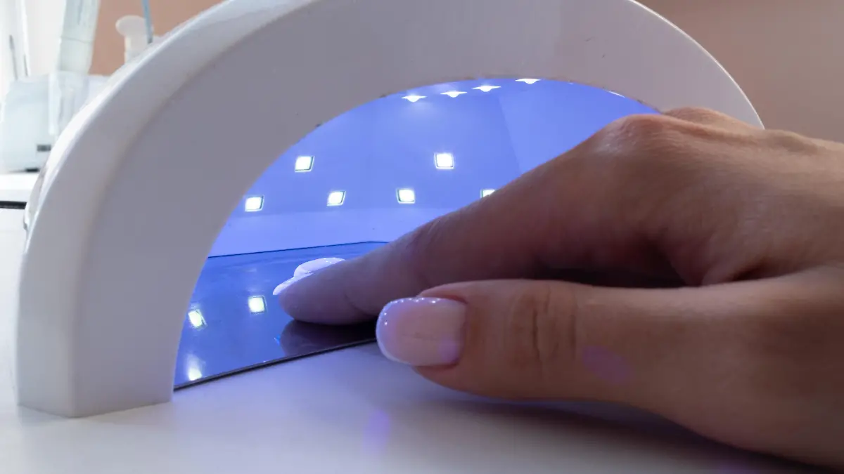 Female hand inside drying UV light machine in nail salon.