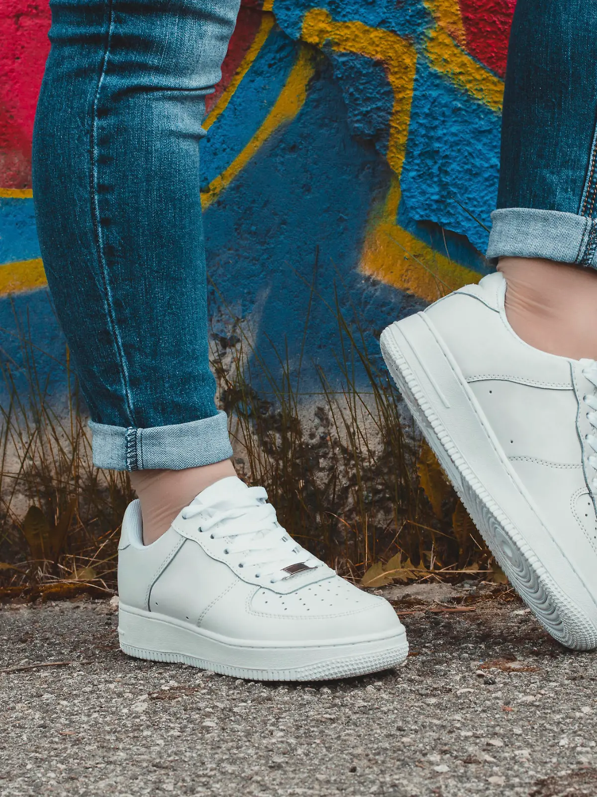 White sneakers on girl legs on the graffiti background