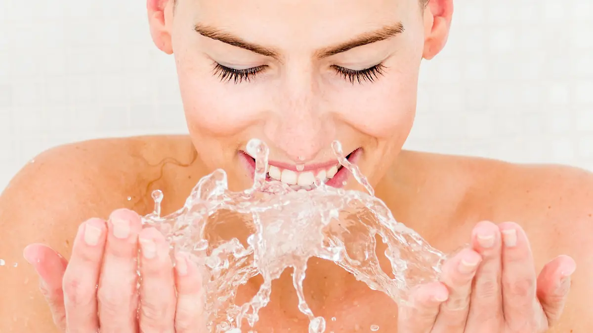 Woman washing her face in the bathroom - beauty concepts