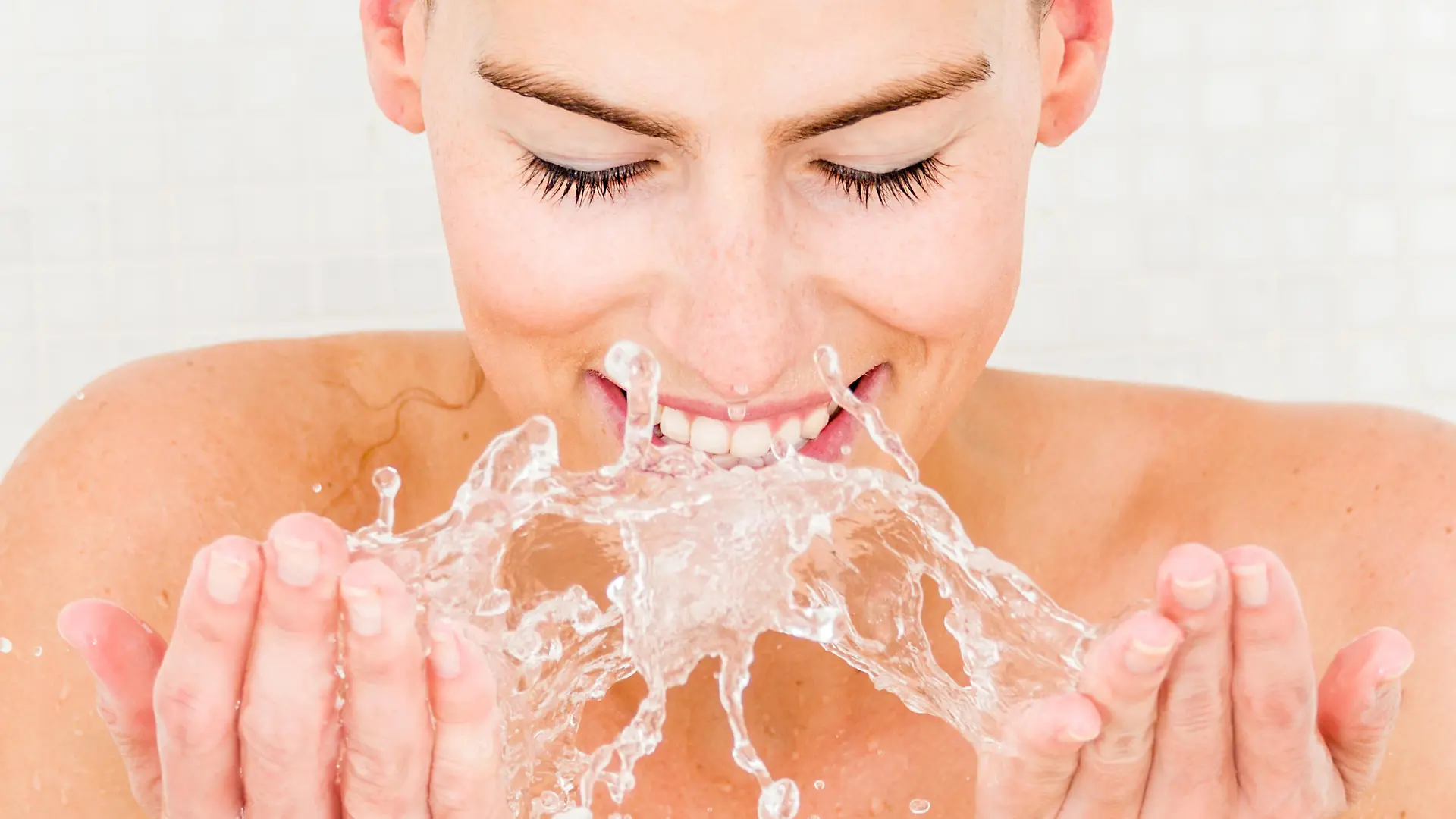 Woman washing her face in the bathroom - beauty concepts